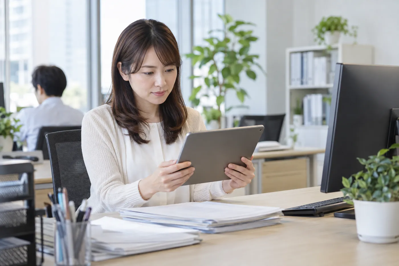 事務所でタブレットを持ち請求内容を確認する事務担当者